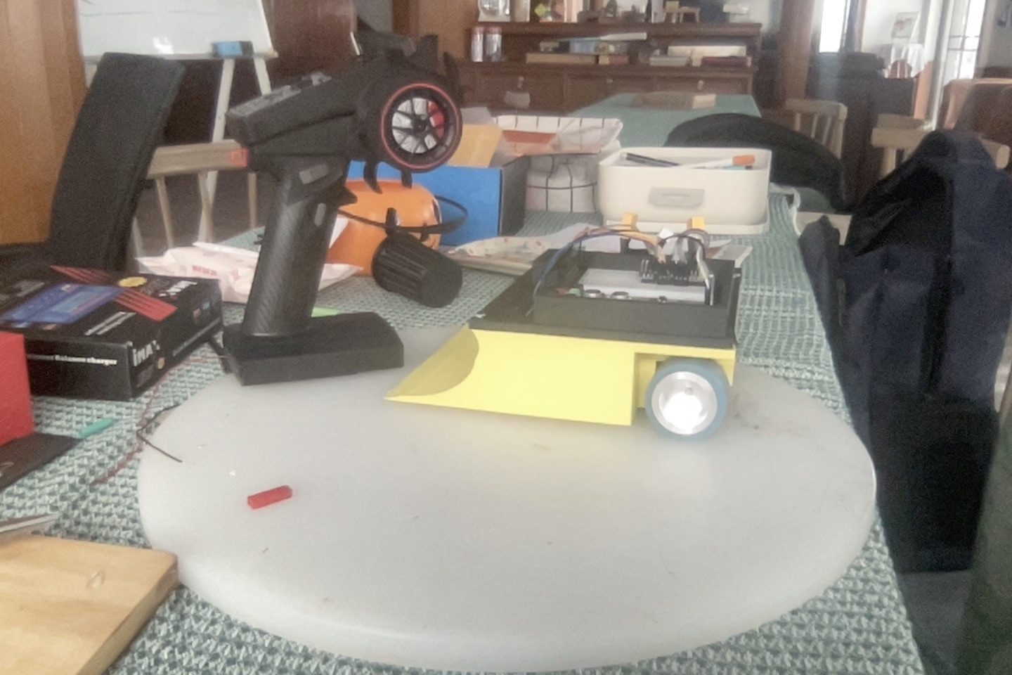 Assembled Version 2 sumo robot with a yellow wedge beside its transmitter