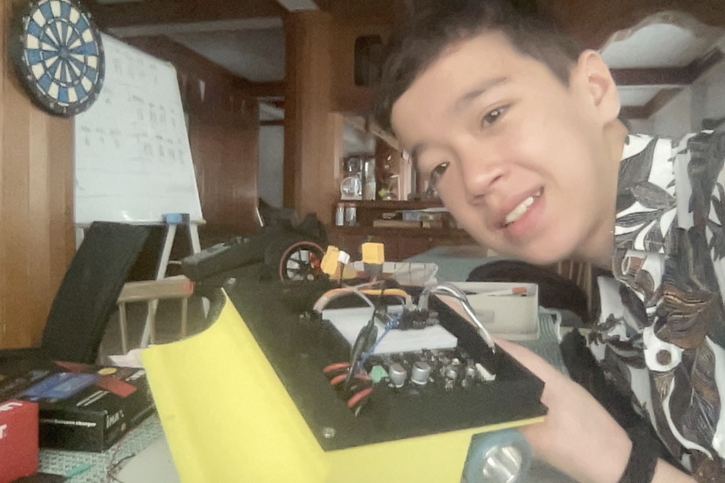 Miles smiling beside his completed yellow and black Version 2 sumo robot