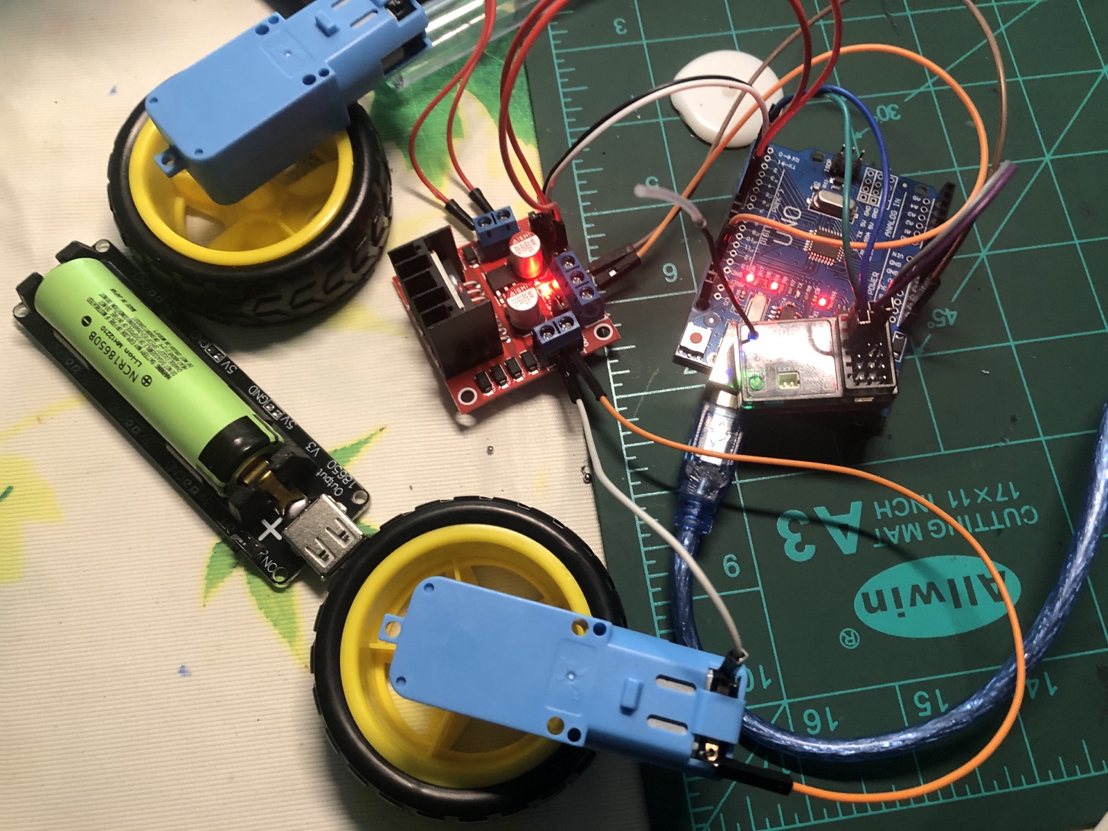 Arduino Uno, L298N motor driver, TT motors and battery holder on the workbench